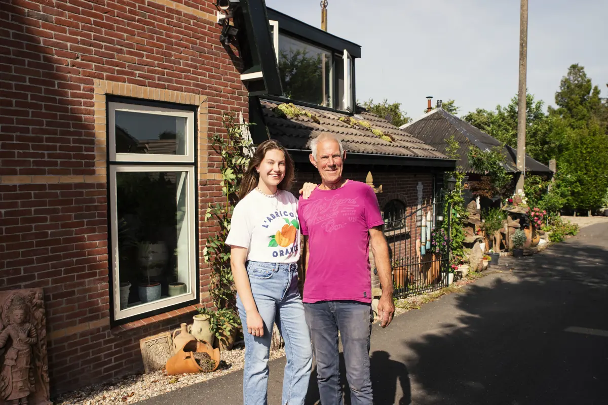 Vader en dochter staan lachend in de achtertuin.