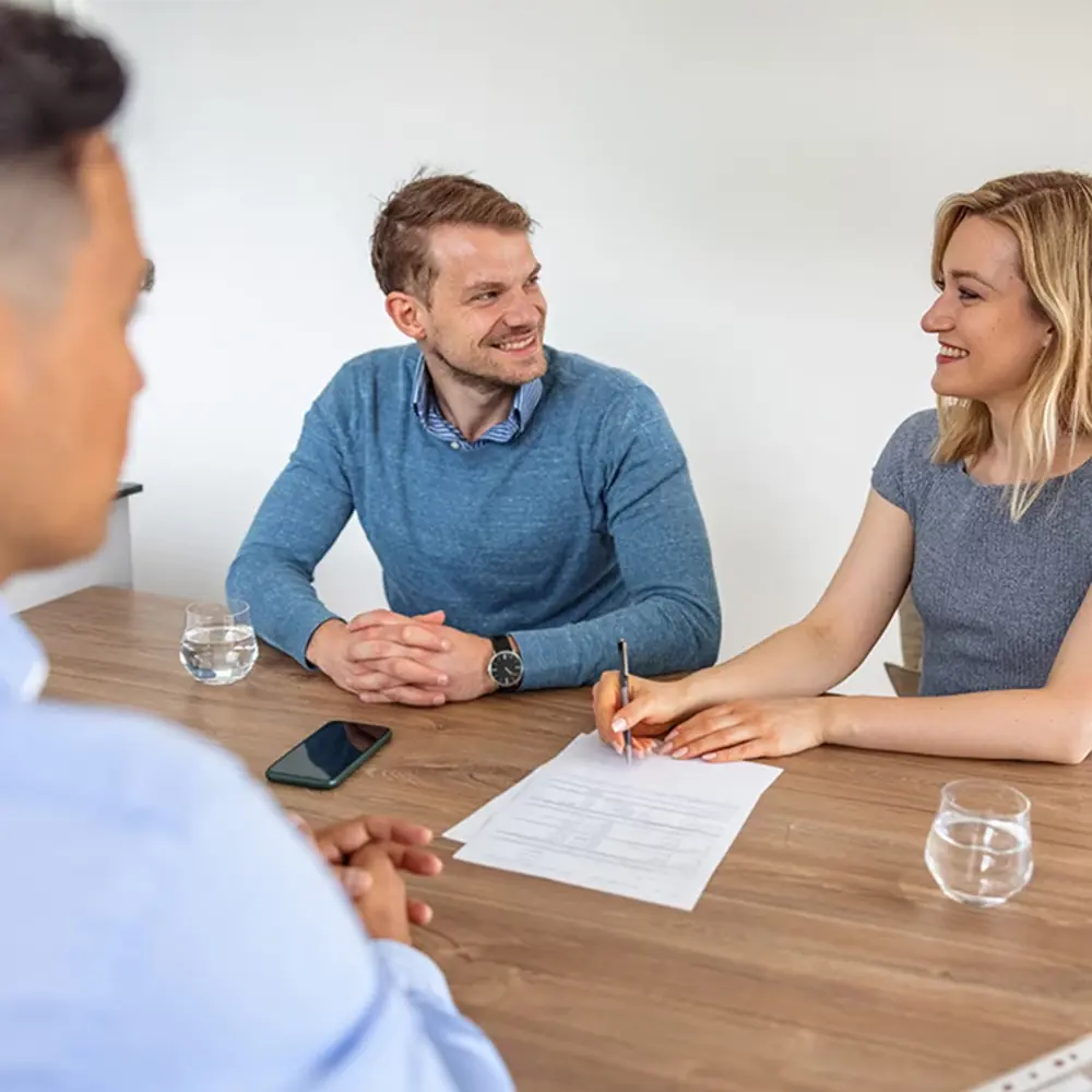 Een stel ondertekent een document bij een adviseur.