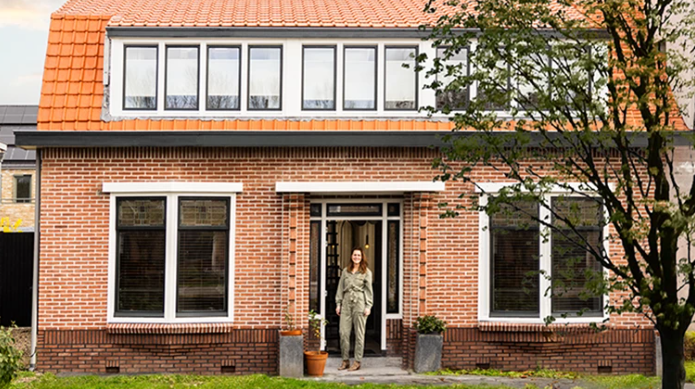 Vrouw staat in de voortuin van haar eigen woning.