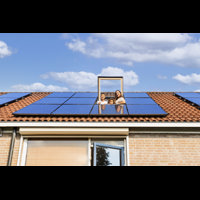 Gezin kijkt door het dakraam naar buiten. Op he dak liggen 10 zonnepanelen.