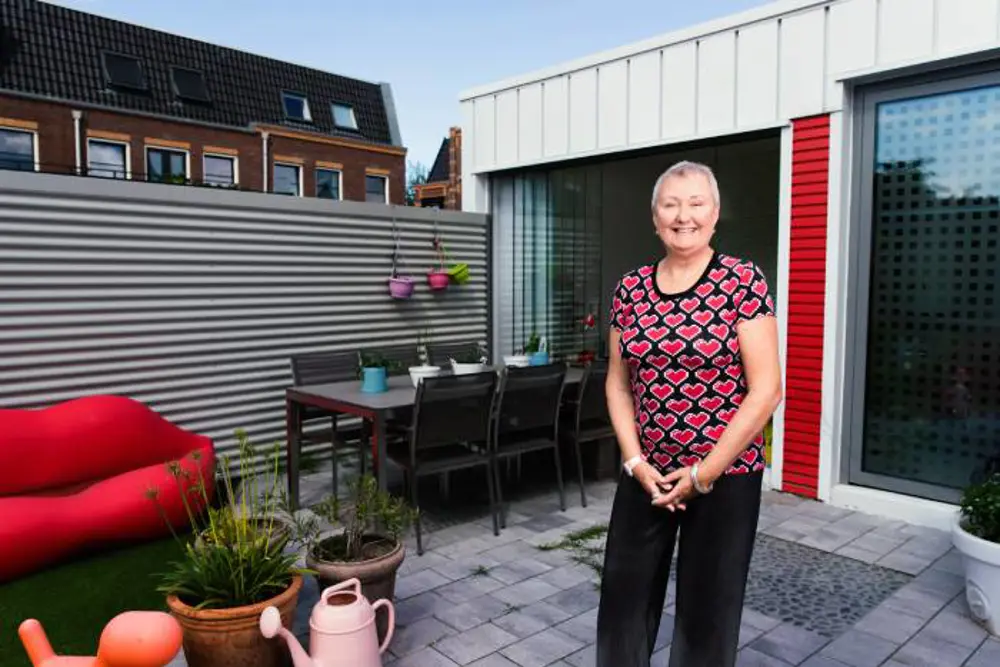 Vrouw in achtertuin van eigen gebouwde huis van zeecontainers