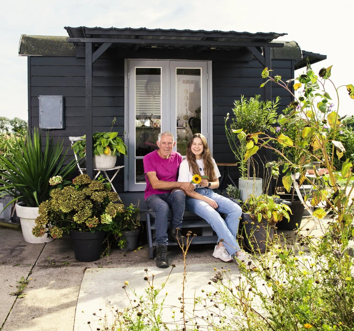 Vader en dochter zitten lachend in een mooie achtertuin